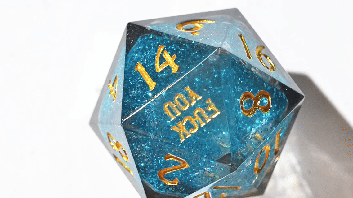 Star Liquid Core RPG Dice – Kickstarter Dice - resin DND D20 die (with gold engraved numbers) spinning on a white